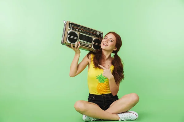 Šťastná mladá rusďouna, která pózovaná přes zelenou zeď s boomboxu. — Stock fotografie