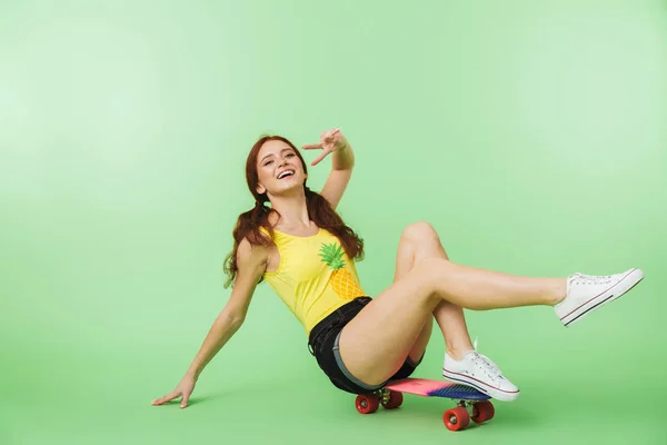Šťastné mladé zrní děvče, které je izolováno na zeleném pozadí se skateboard. — Stock fotografie