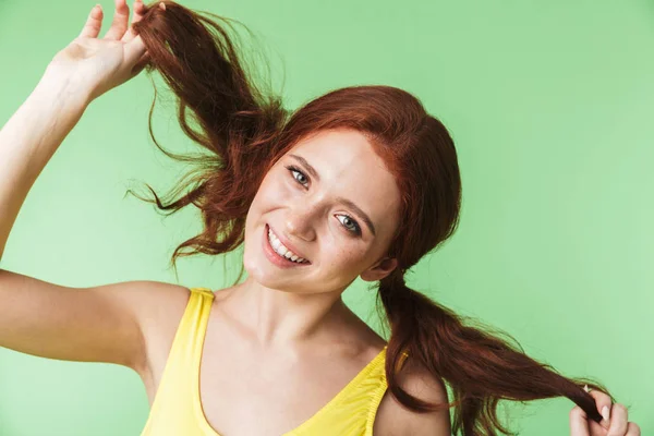 Güzel mutlu genç kızıl saçlı kız yeşil duvar arka plan üzerinde izole poz. — Stok fotoğraf
