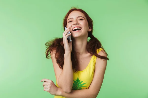 Menina ruiva bonita posando isolado sobre fundo parede verde falando por telefone móvel . — Fotografia de Stock