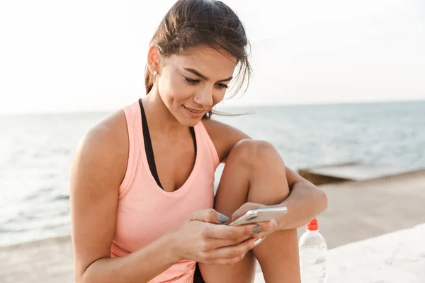 Atrakcyjna młoda kobieta fitness za pomocą telefonu komórkowego — Zdjęcie stockowe