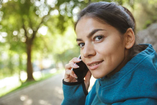 Sportswoman sorrindo falando no telefone celular — Fotografia de Stock