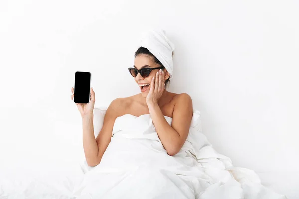 Изображение возбужденной женщины 30 лет в солнечных очках, завернутых в одеяло — стоковое фото