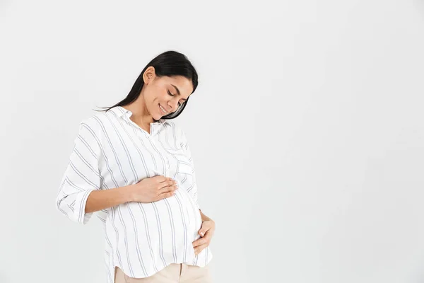 Изображение нежной беременной женщины 30 лет, улыбающейся и трогающей свою большую — стоковое фото