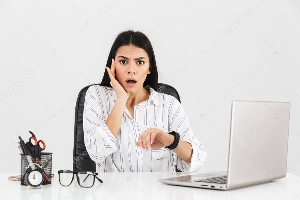 Photo of puzzled brunette businesswoman 30s looking at wristwatc