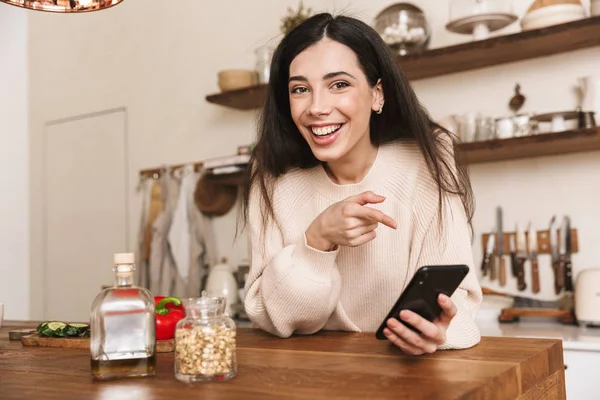 Porträtt av Brunette hemmafru 30s Holding smartphone medan Cook — Stockfoto