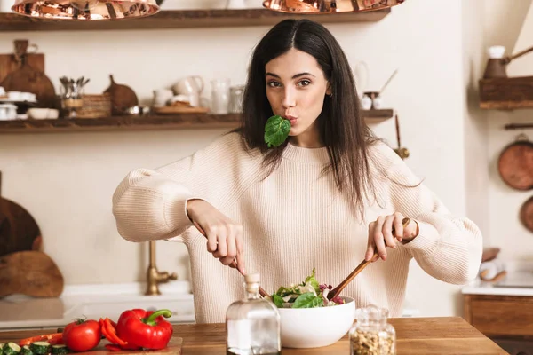 Изображение молодой брюнетки, которая ест здоровый зеленый салат с вином — стоковое фото