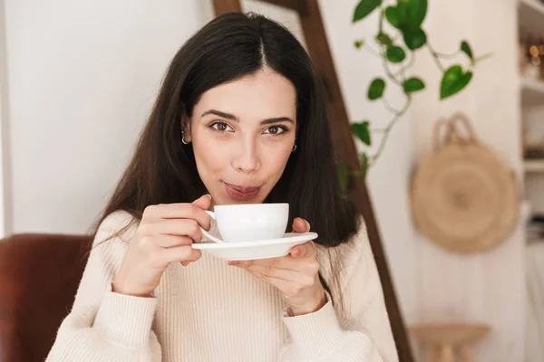 Beeld van schattige brunette vrouw drinken koffie terwijl het hebben van on — Stockfoto