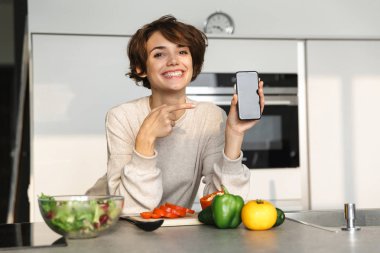Boş akıllı telefon ekranı gösteren mutlu esmer kadın