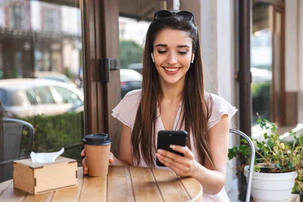 Улыбающаяся красивая женщина сидит в кафе на открытом воздухе — стоковое фото