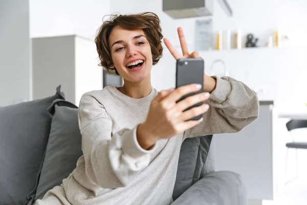 Smilende brunettdame som lager selfie på smarttelefon – stockfoto