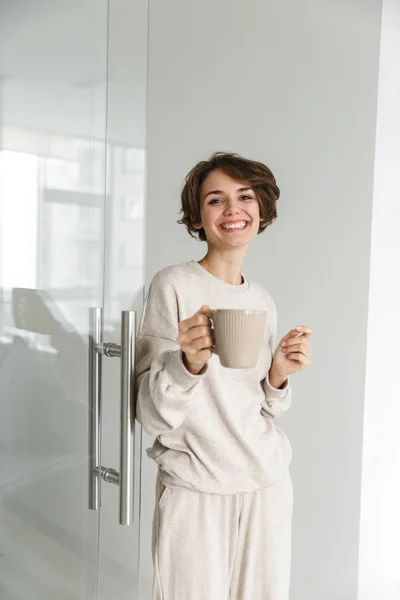 Verticale afbeelding van lachende brunette vrouw drinkng koffie — Stockfoto