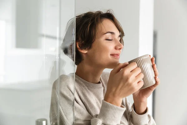 Agradable morena bebiendo café con los ojos cerrados y disfruta — Foto de Stock