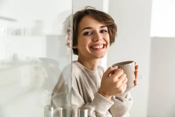 コーヒーを飲む笑顔のブルネット女性の側面図 — ストック写真