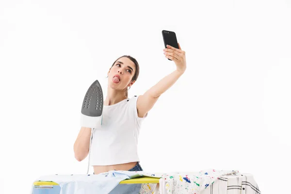 Photo of young woman housewife 20s holding mobile phone and taki — Stock Photo, Image