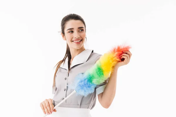 Foto de la sonriente criada de 20 años vestida de uniforme sosteniendo colorido du — Foto de Stock