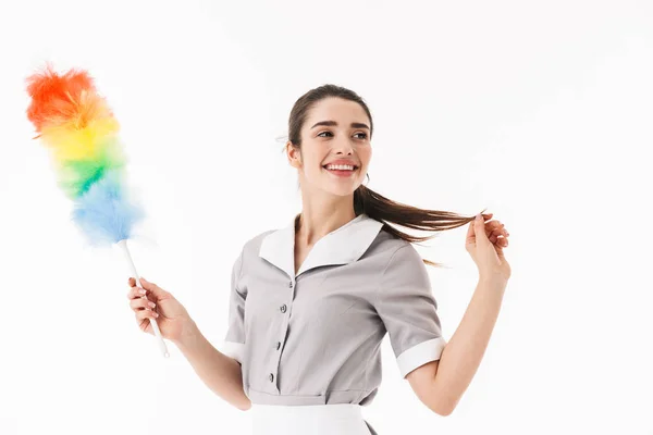 Foto de bonita mucama de 20 años vestida con uniforme sosteniendo colorido dus — Foto de Stock