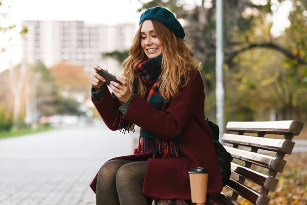 Palto ve bere giyen güzel genç kadın oturuyor