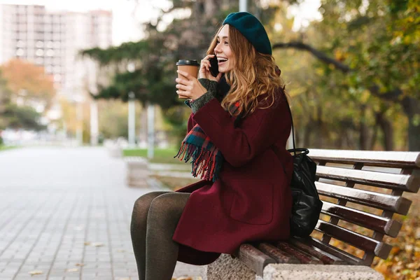 Palto ve bere giyen güzel genç kadın oturuyor