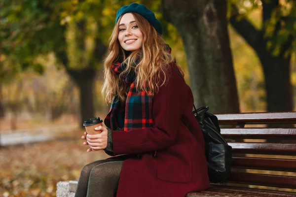 Bella giovane donna che indossa cappotto e basco seduta — Foto Stock