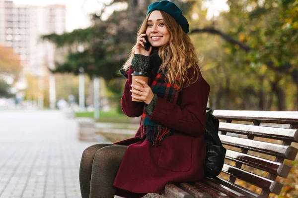 Lovely young woman wearing coat and beret sitting — Stock Photo, Image