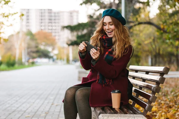 Palto ve bere giyen güzel genç kadın oturuyor