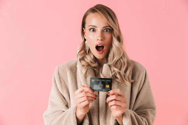 Geschokt blonde vrouw dragen in bont jas Holding creditcard — Stockfoto