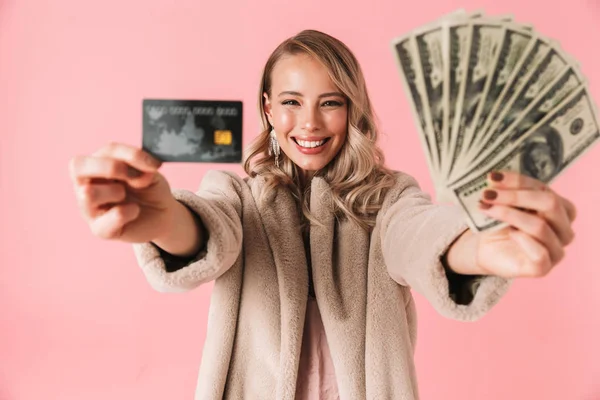 Glückliche blonde Frau im Pelzmantel, die Geld zeigt — Stockfoto