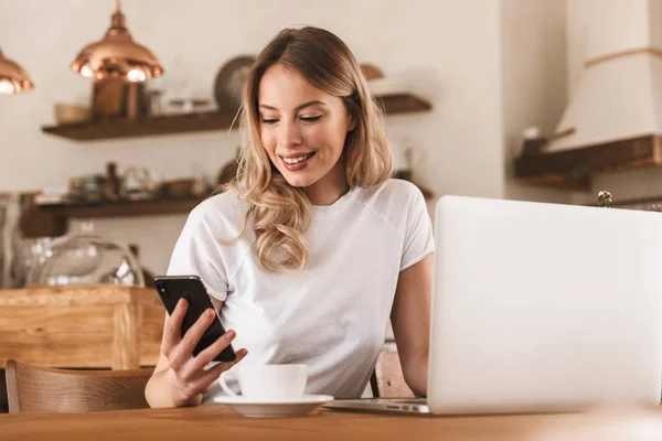 Retrato de mulher loira atraente trabalhando em laptop e bebendo — Fotografia de Stock