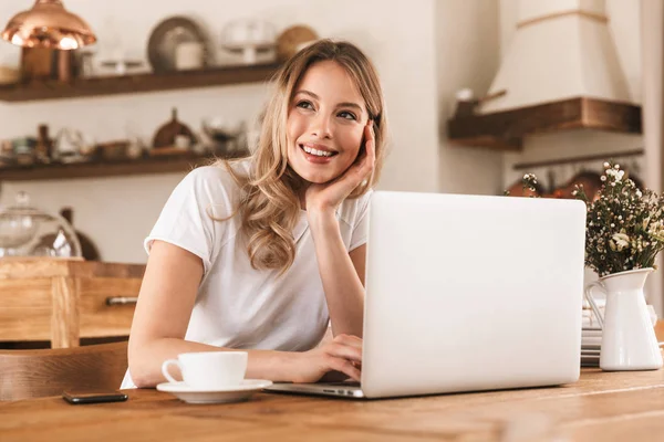 Retrato de mujer rubia caucásica trabajando en el ordenador portátil y bebiendo — Foto de Stock