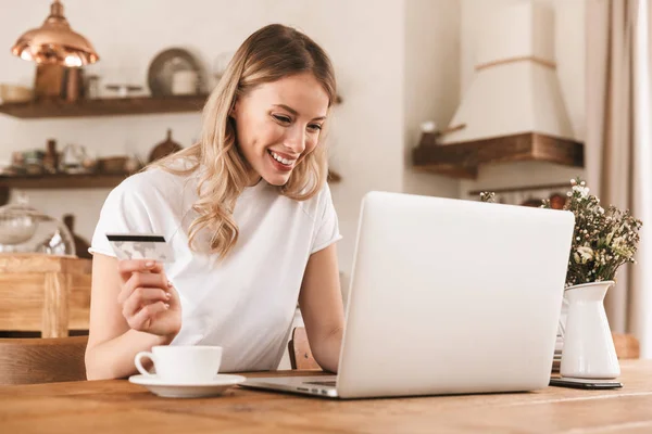 Retrato de mulher loira satisfeita usando laptop e cartão de crédito f — Fotografia de Stock