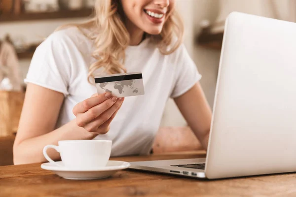 Retrato de mujer rubia encantadora usando el ordenador portátil y la tarjeta de crédito fo — Foto de Stock