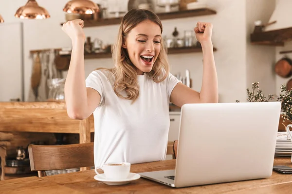 Porträt einer fröhlichen blonden Frau, die bei der Arbeit am Laptop jubelt — Stockfoto