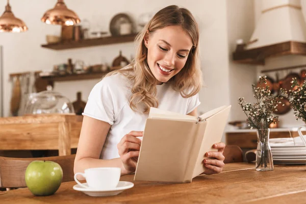Портрет европейской блондинки, читающей книгу и пьющей кофе — стоковое фото