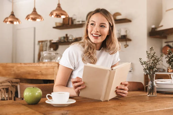 本を読んでコーヒーを飲むスマートなブロンドの女性の肖像画w — ストック写真