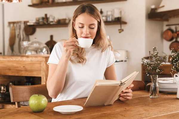 Portré bájos szőke nő olvasókönyv és ivás kávé — Stock Fotó