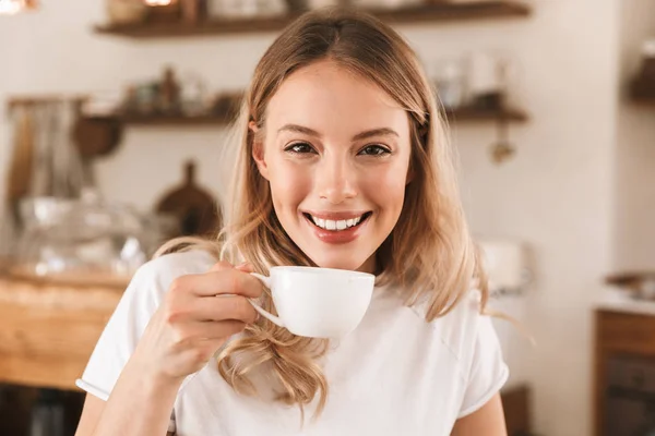 Portrait of lovely blond woman drinking tea while sitting in coz — Stock Photo, Image