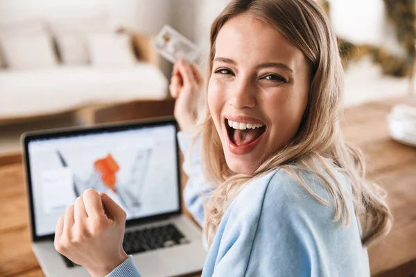 Portret podekscytowany blond kobieta 20s za pomocą laptopa i karty kredytowej — Zdjęcie stockowe
