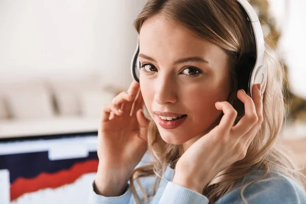 Portret van jonge blonde vrouw 20s het dragen van een koptelefoon met behulp van lapto — Stockfoto