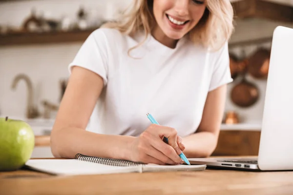 Bild av Söt blond kvinna 20s klädd i vit t-shirt studerar på — Stockfoto