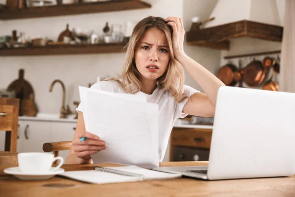 Kép a zavarodott szőke nő tanul a laptop és az írás nem — Stock Fotó