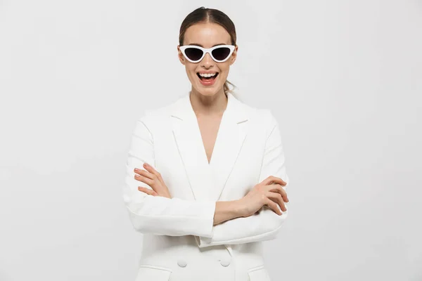 Belle femme heureuse posant isolée sur fond de mur blanc portant des lunettes de soleil . — Photo