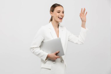 Şaşırtıcı kadın beyaz duvar arka plan üzerinde dizüstü bilgisayar sallayarak tutarak izole poz.