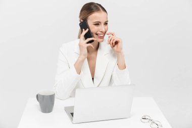 Cep telefonu ile konuşan dizüstü bilgisayar kullanarak beyaz duvar arka plan üzerinde izole poz Amazing kadın.