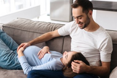 Mutlu genç hamile çift bir kanepede rahatlatıcı