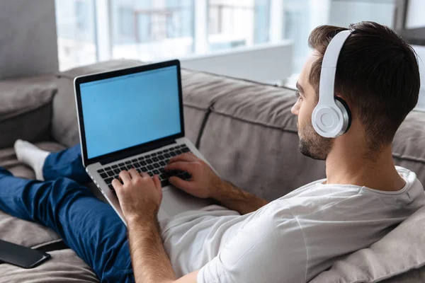 Photo of modern guy in headphones holding and using silver lapto — Stock Photo, Image