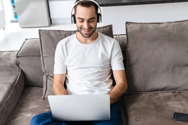 Foto del tipo de contenido en auriculares sosteniendo y usando lapt plateado — Foto de Stock