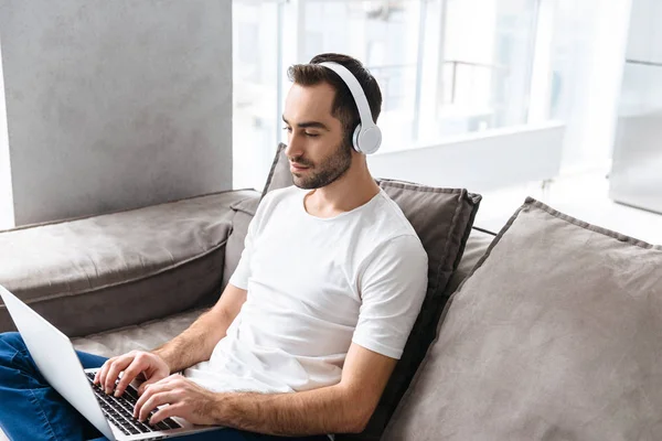 Foto de cara masculino em fones de ouvido segurando e usando prata la — Fotografia de Stock