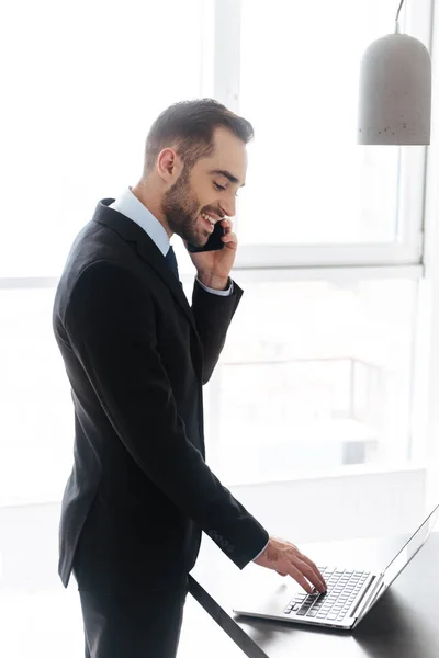 Kuva nuoresta liikemiehestä puhumassa matkapuhelimella työskennellessään — kuvapankkivalokuva