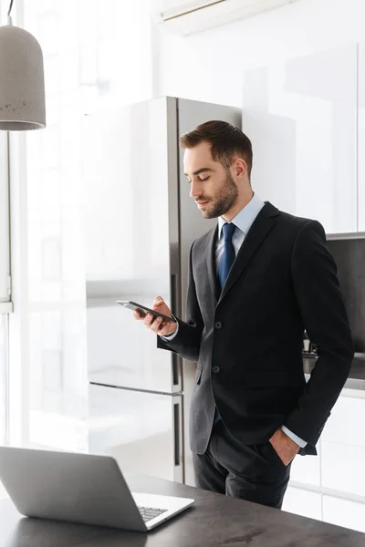 Afbeelding van brunette zakenman met behulp van mobiele telefoon tijdens het werken o — Stockfoto